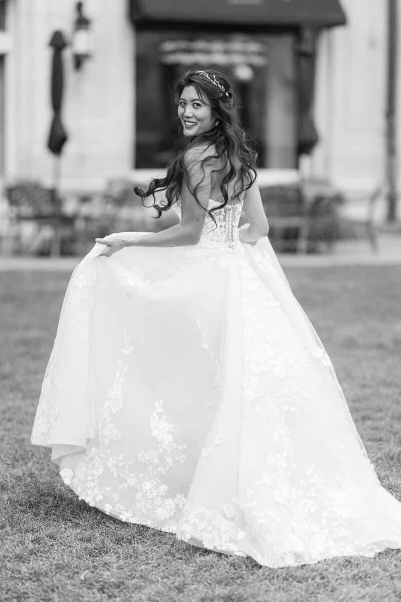 This portrait features a bride on the lush lawn of the Banff Springs Hotel, captured as she walks away then glances back, smiling at the camera. Her joyful expression and the elegant backdrop of the hotel create a timeless moment during her photo session.