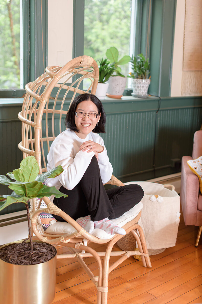 A woman sitting on the couch with her legs crossed and smiling.