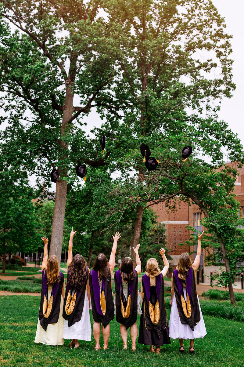 Girls wearing dresses and law school hoods tossing their gaps on the Vanderbilt campus at sunset