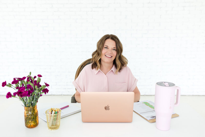 Your dedicated Women’s Health Provider at Reforme Wellness is seated at a white desk with a laptop, accompanied by patient notes and agendas for a discovery wellness call.