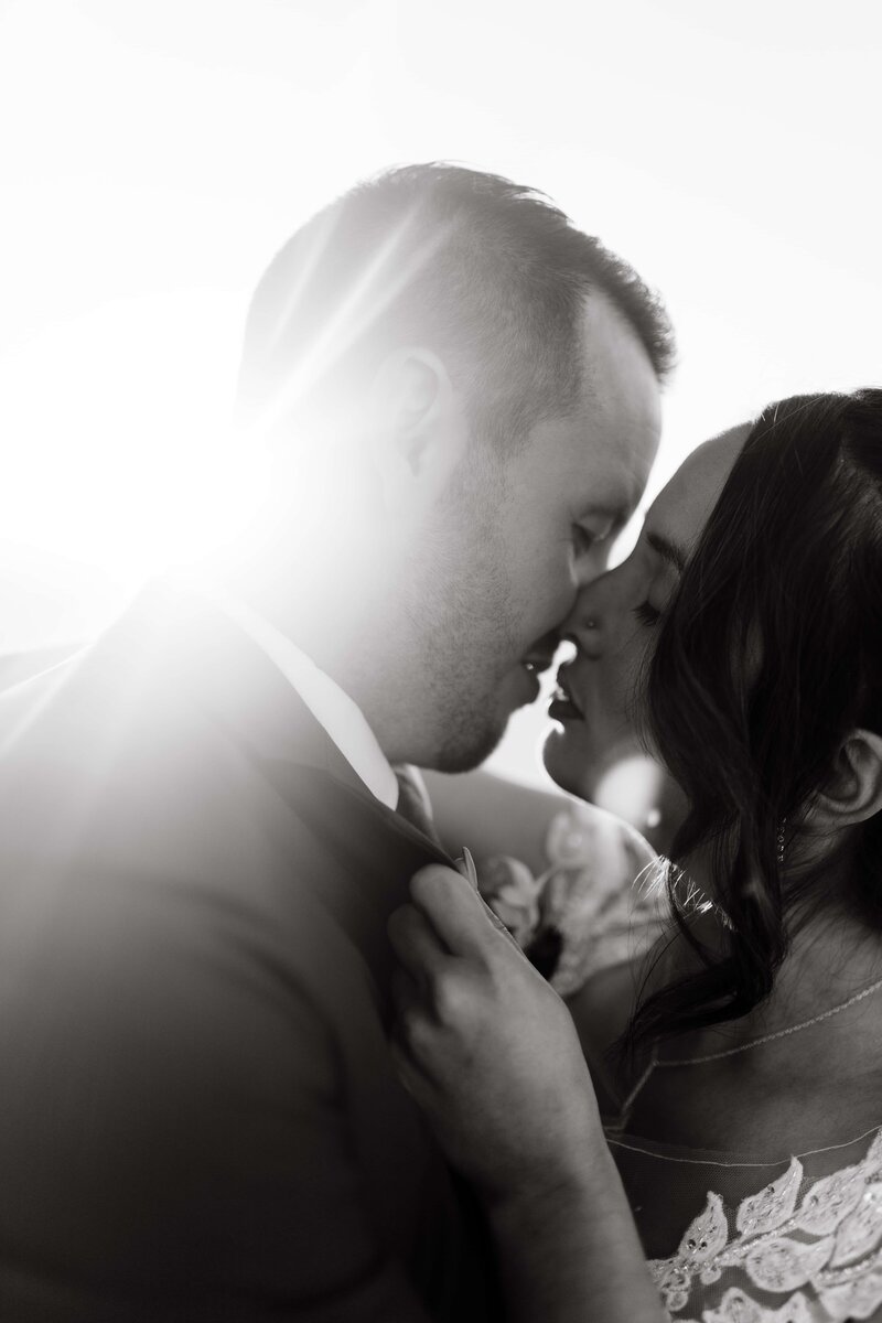 black and white photo of couple about to kiss while the sun streams in behind them