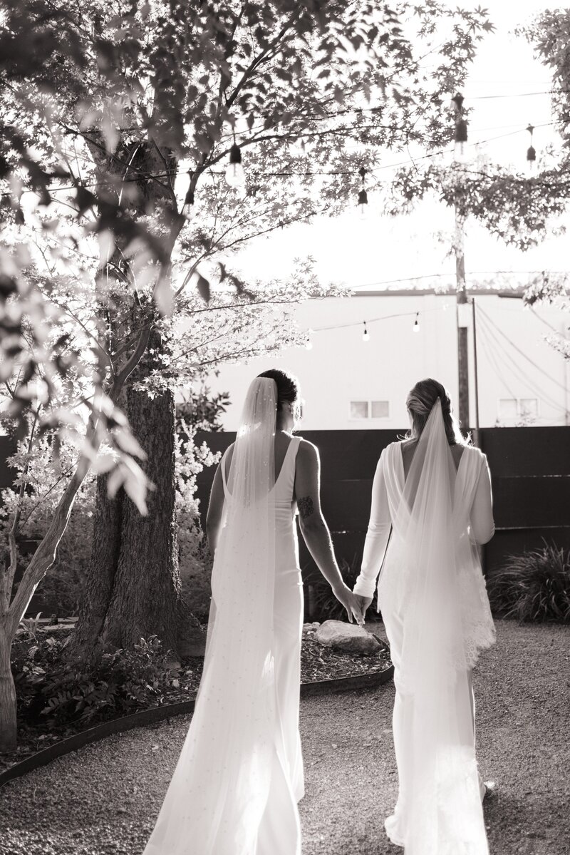 brides holding hands and walking away from the camera