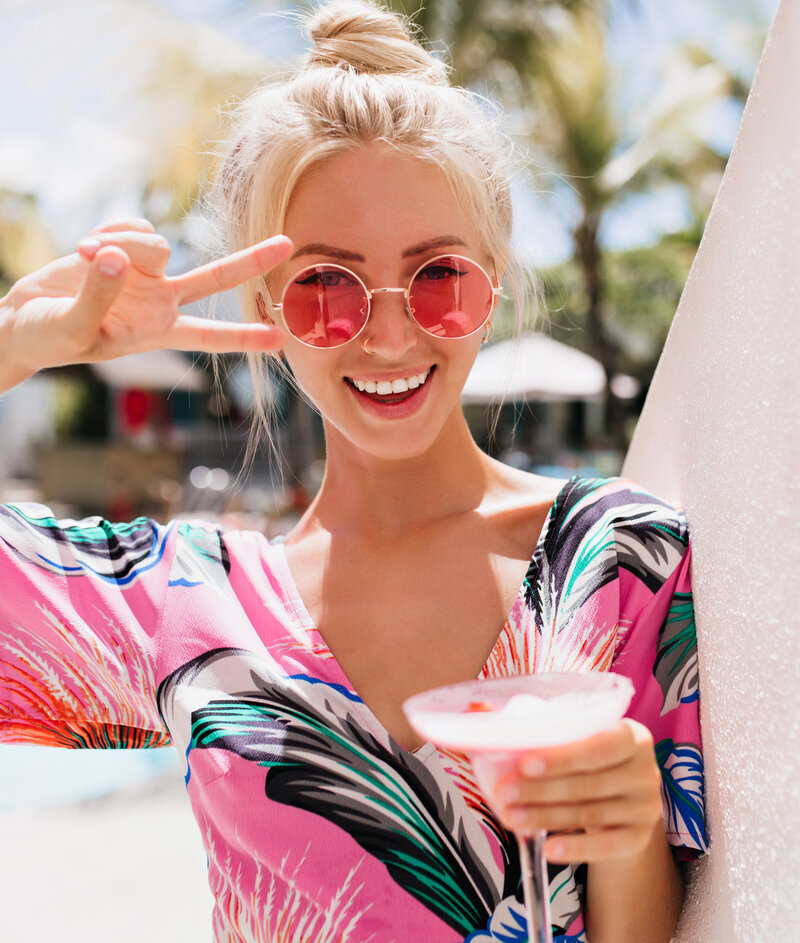 portrait-blissful-blonde-woman-posing-with-peace-sign-drinking-cocktail-happy-tanned-caucasian-girl-bright-dress-having-fun-summer-resort copy