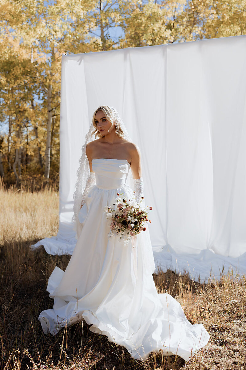 Bride posing during bridal portraits with a draped backdrop in park city.