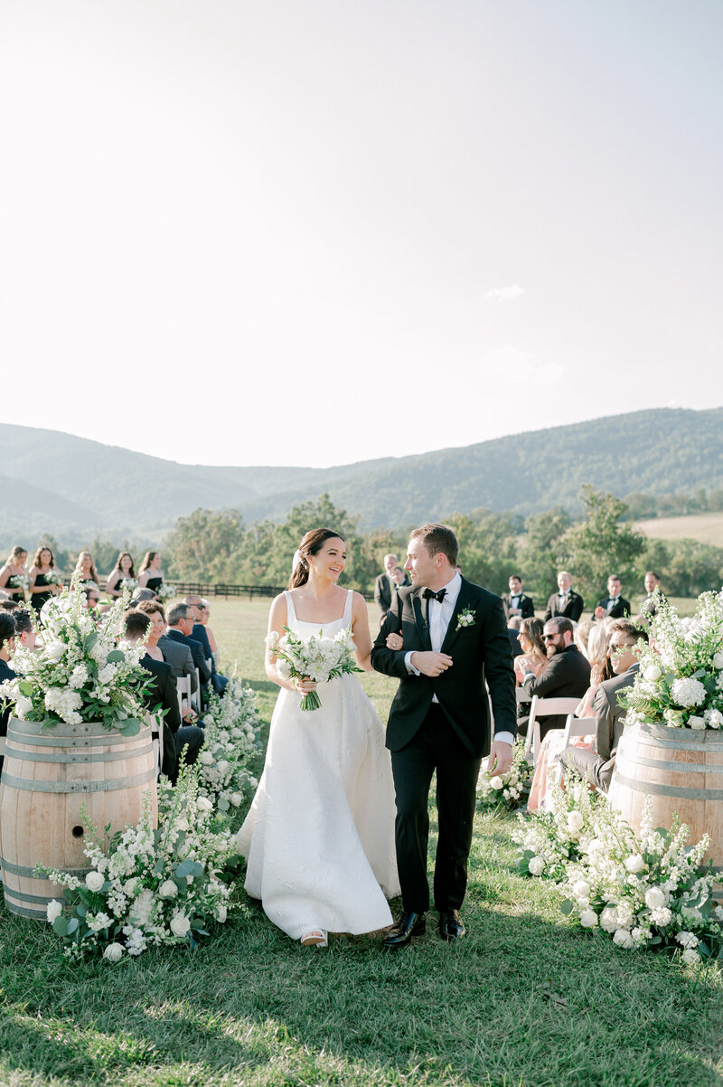 a bride and groom looking at each other as they walk down the aisle