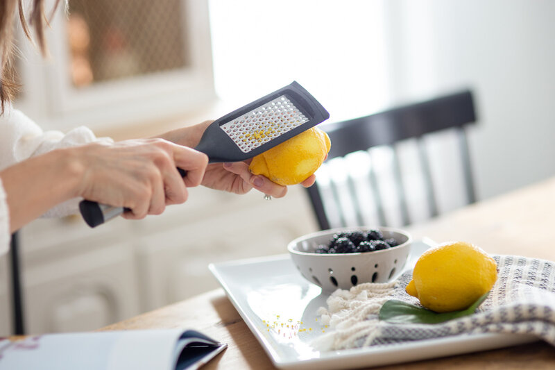 Close up of lemons being grated and bowl of blueberries styled kitchen scene