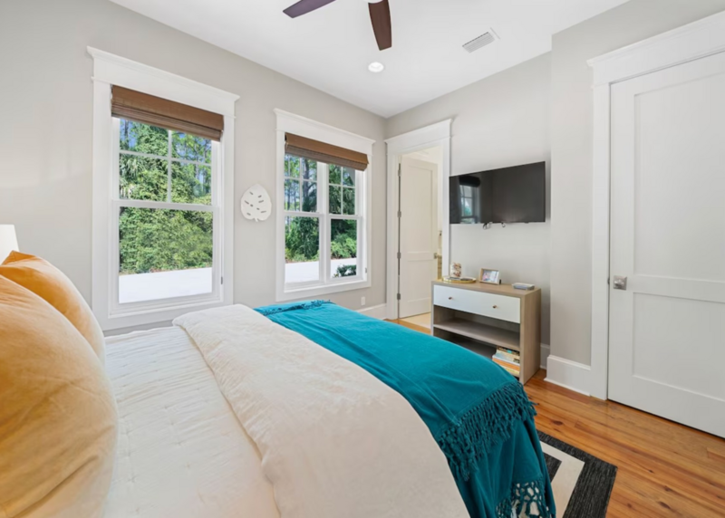 bedroom with white linens, blue blanket, and yellow pillows