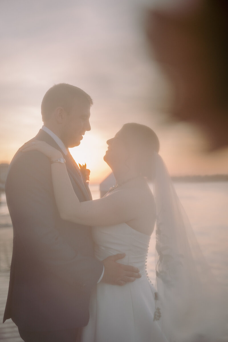 bride and groom embracing while standing on the beach