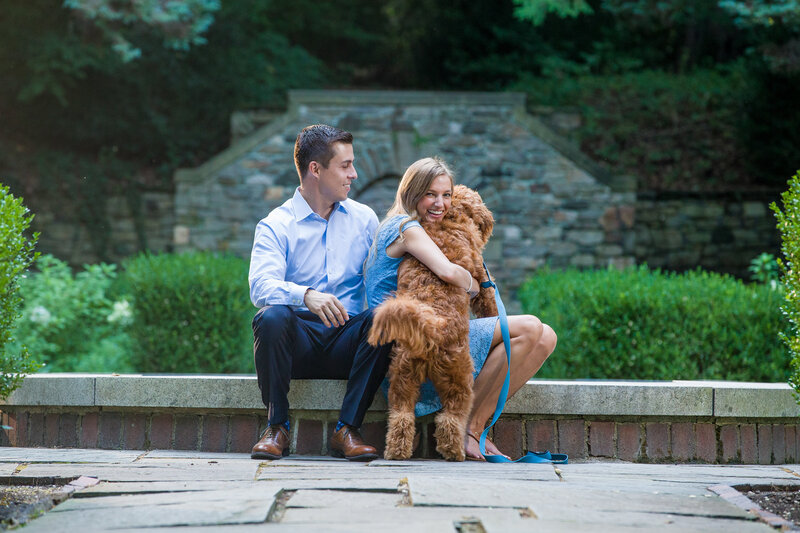Couple laughing as she hugs their dog tighter than her groom-to-be, creating a playful and dog-loving engagement photo.