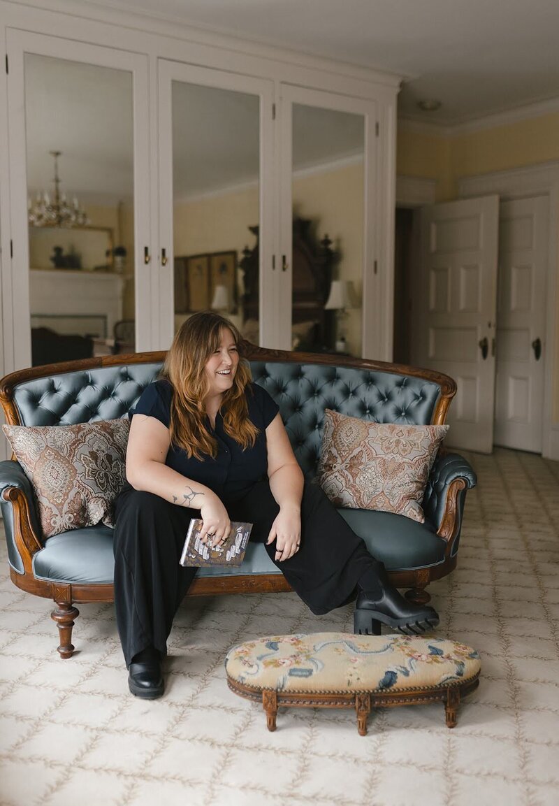 Woman sitting in an old building on a blue couch holding a book