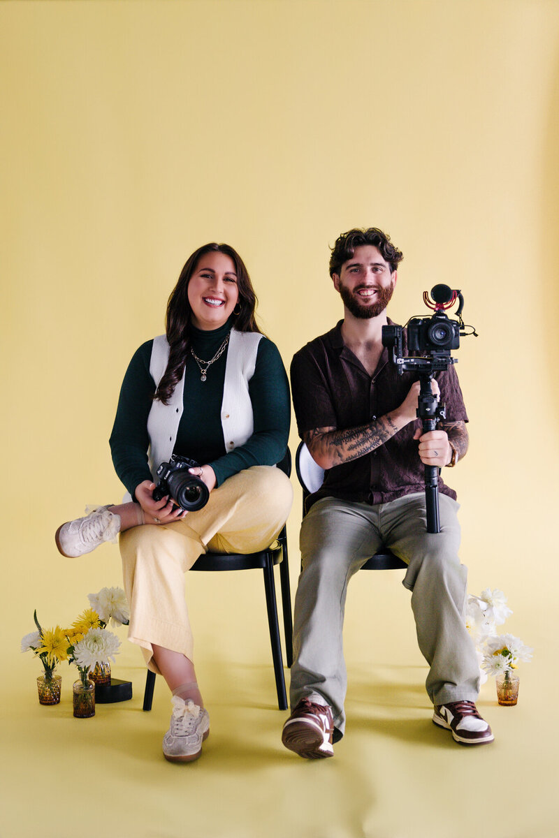 A person leaning over their partner's shoulder while they sit in a chair