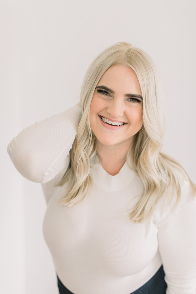 Your EMDR therapist, Megan Zuzevich, poses for the camera with her hand on her neck. She is able to help with trauma, vicarious traumatization, secondary trauma, generalized anxiety disorder and more in the Los Angeles County area with online therapy in California.