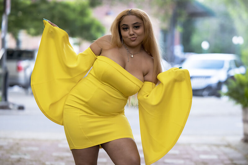 Senior girl with blonde hair in short yellow dress with big sleeves posing playfully holding up peace signs