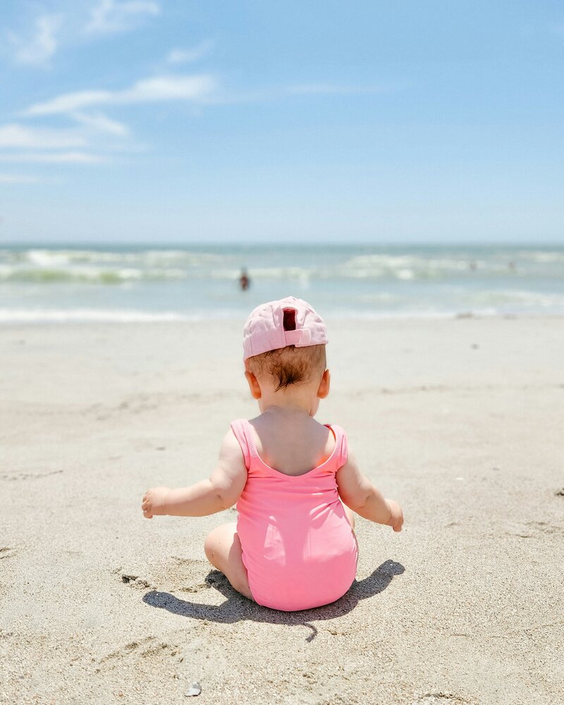baby in pink swimsuit on beach