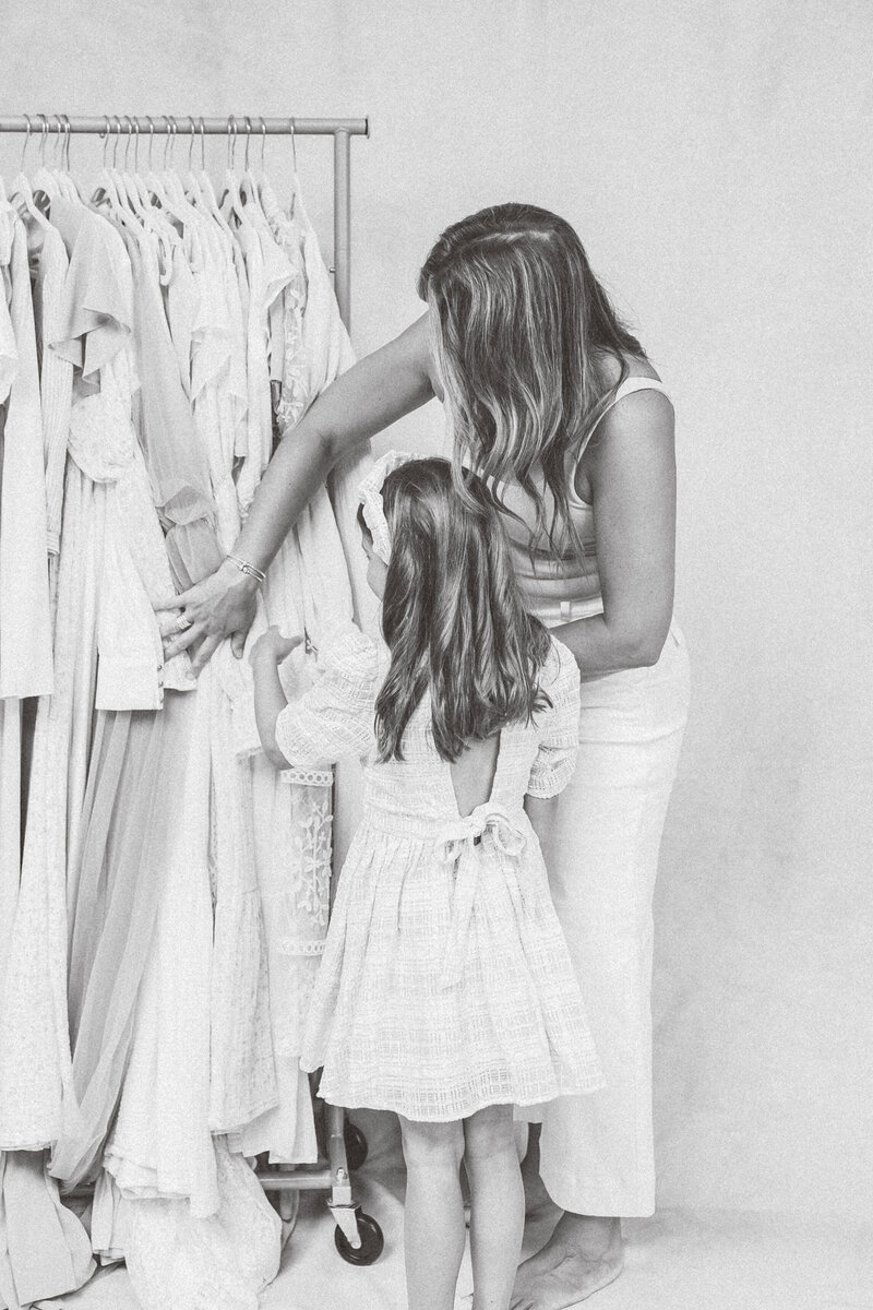 Photographer assisting a client with wardrobe styling from a curated collection before a maternity session.
