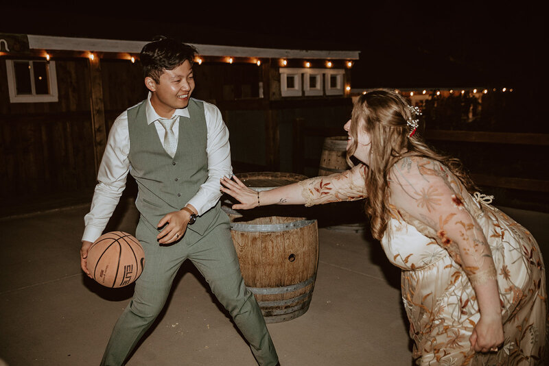 bride and groom play basketball at night 