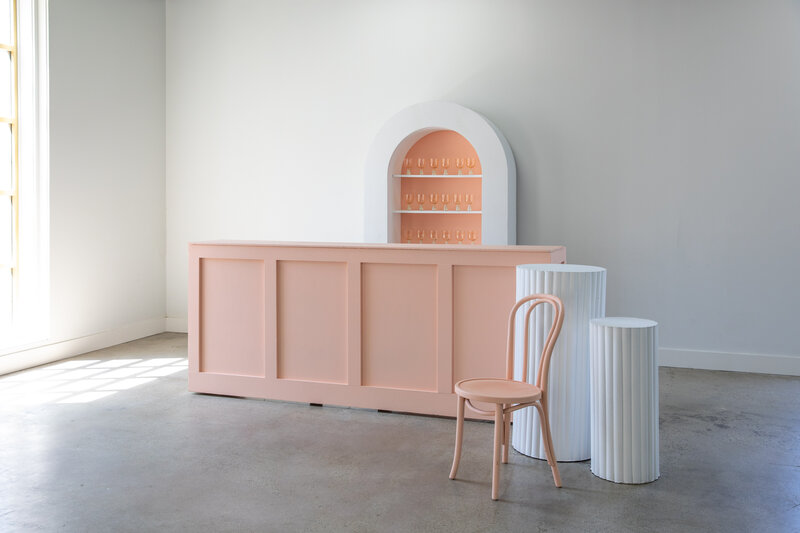8' Peach Bar, Back Bar Shelf with white outline and peach on the inside, two white pedestals, and one peach bentwood chair
