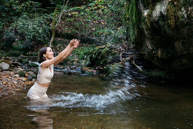 woman standing in a river playing with water