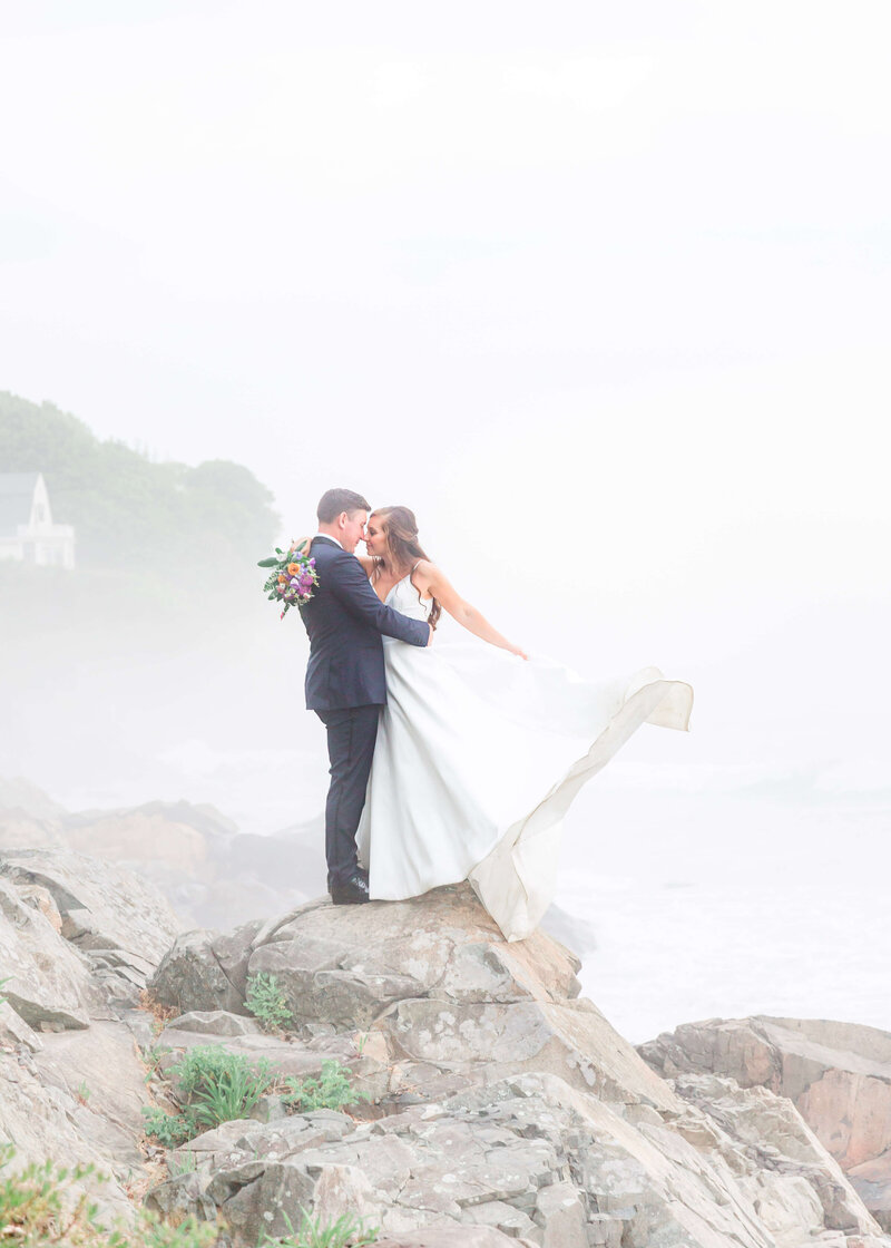 adventurous bride and groom standing on rocks at York Harbor beach for york Inn Wedding  (14)