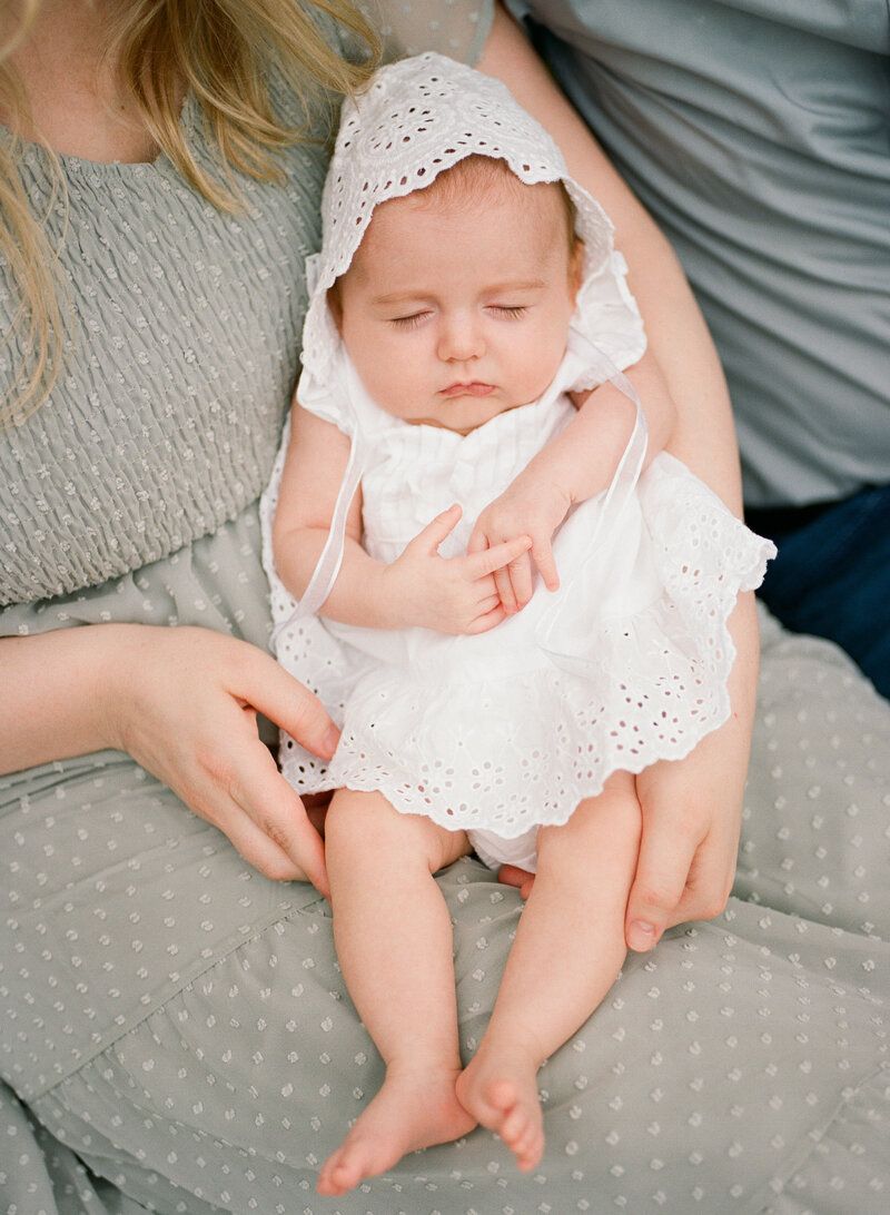 Baby girl sleeping in her mother’s arms during an in-home photography session in Longmont, Colorado.