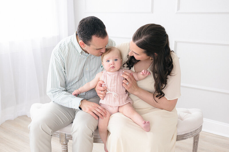 Family of three sitting on a bench in a bright louisville kentucky photography studio