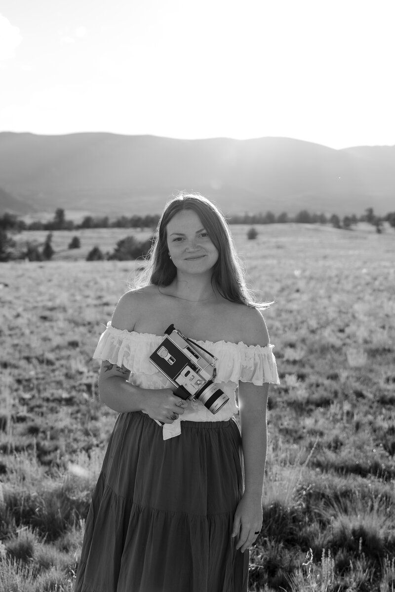 woman shooting super 8 film in a field in summer