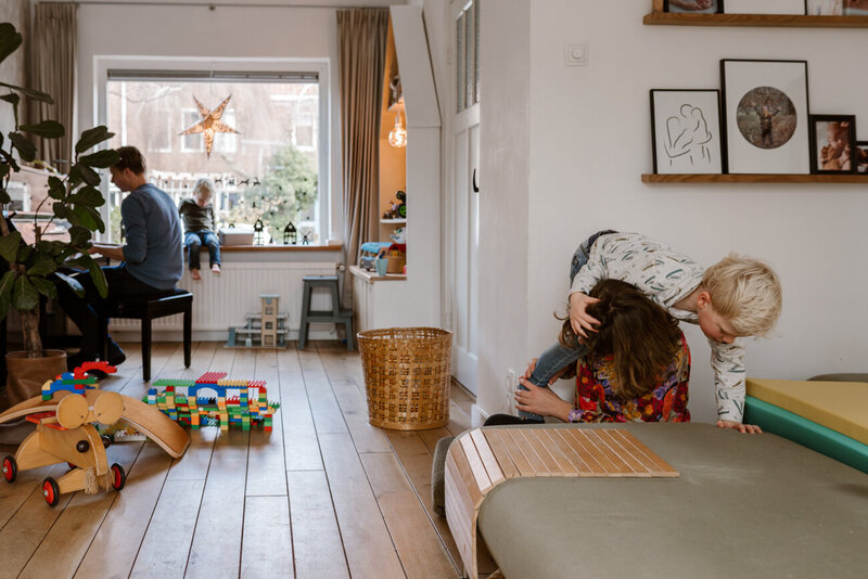 gezinsfoto thuis in de huiskamer samen stoeien