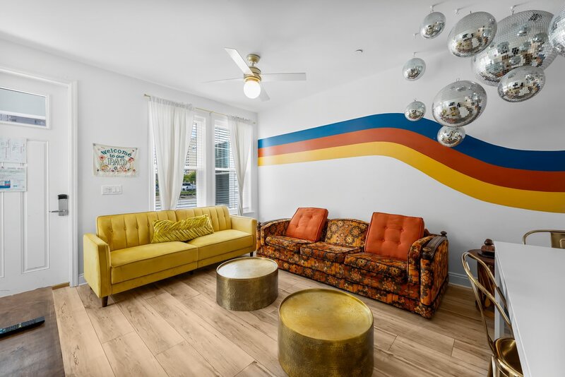 Groovy Shack living room with a mustard yellow couch, burnt orange loveseat, gold accents, and disco decor perfect for content creators.