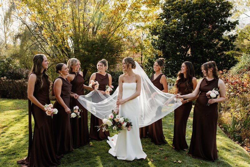 Bride laughing with bridesmaids in soft sunlight, every detail of joy captured