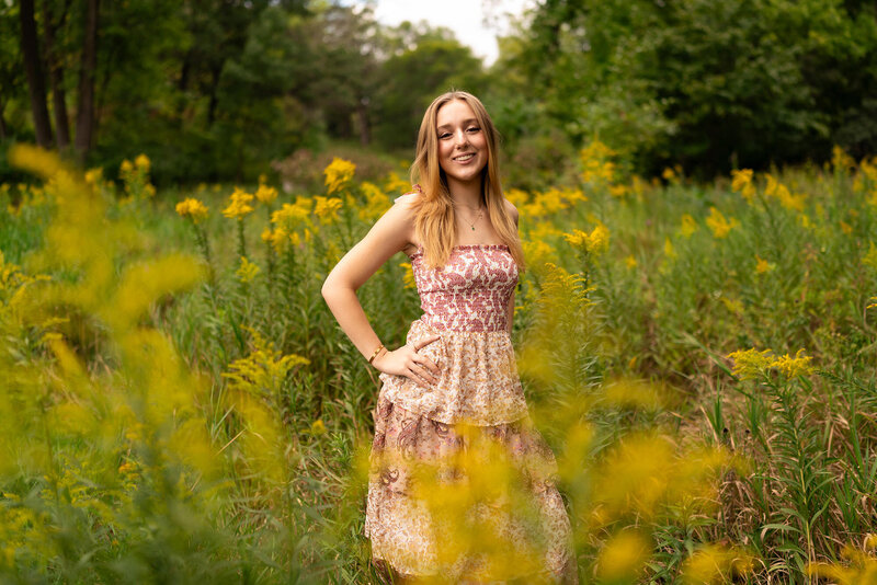 Senior girl with glasses dressed in T-shirt laughs during senior photography