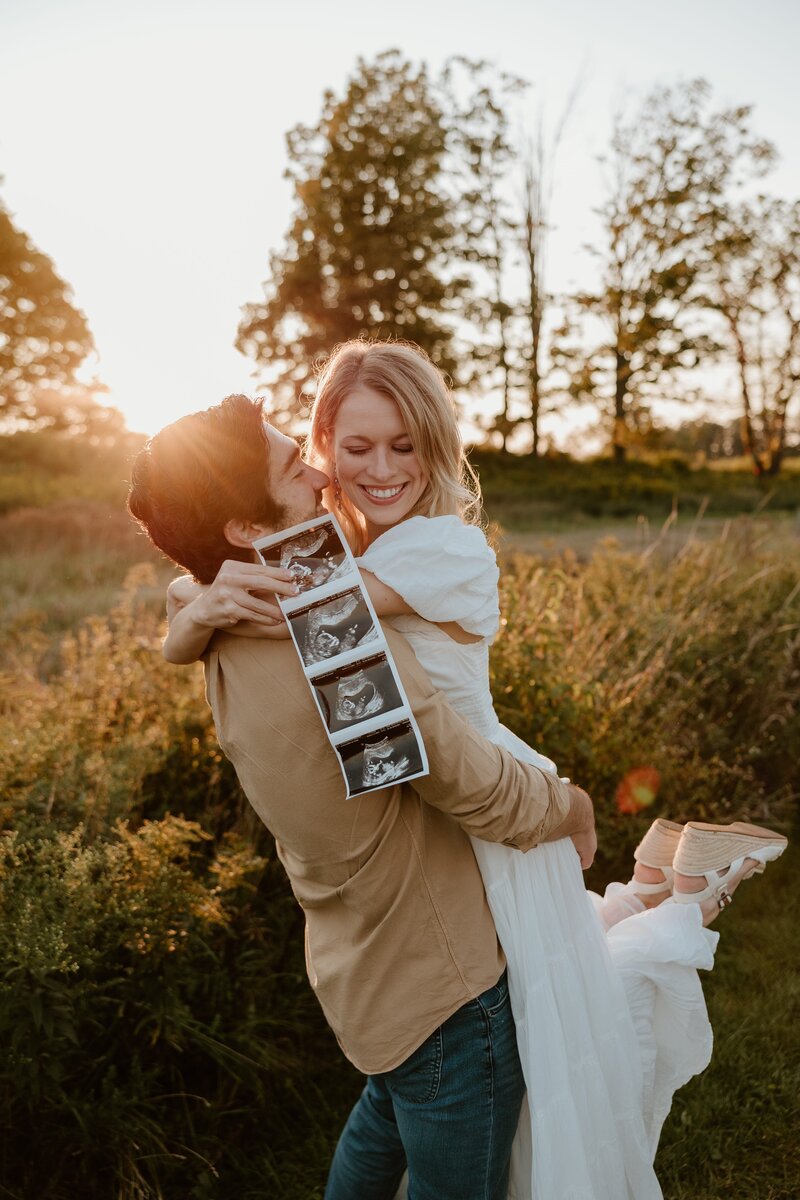 Couple announcing pregnancy holding ultrasound photo.