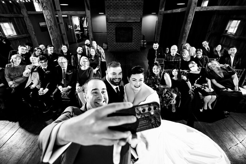 A wedding officiant taking a selfie with the bride and groom during the ceremony at Cornman Farms in Dexter Michigan