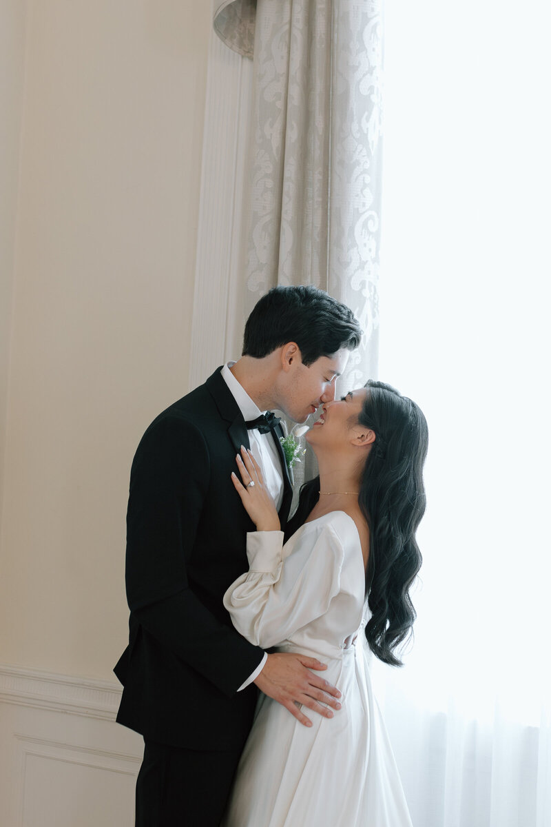 A close and intimate moment between a bride and groom in front of a fireplace, surrounded by elegant wedding decor.