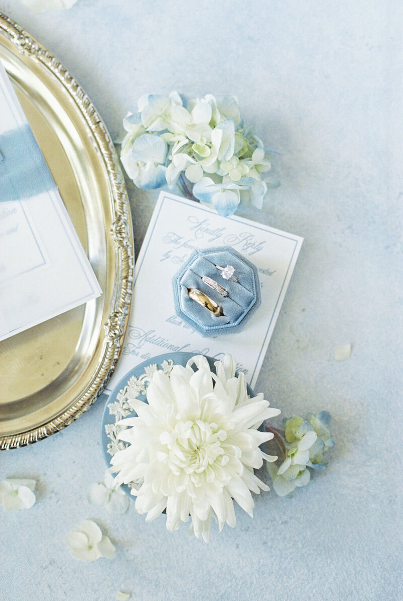Wedding details flat lay on blue background with white flowers
