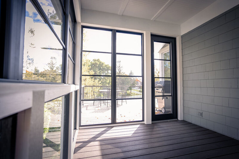 Inside an empty 3-season porch with TimberTech flooring, 4-panel vinyl windows, and beadboard ceiling. 