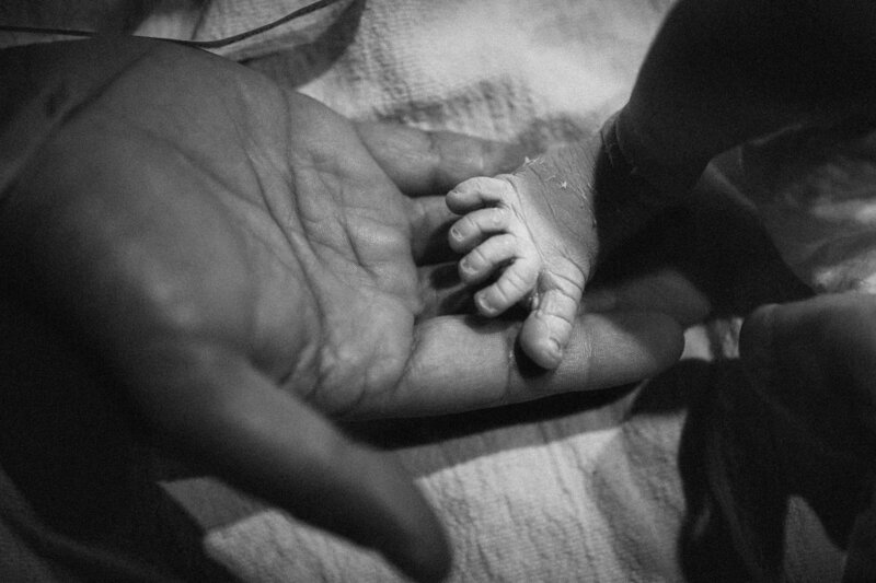 father holding newborn foot at birth