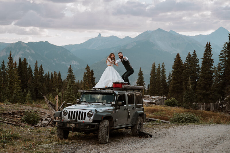 Wedding couple standing on top of a Jeep with mountain views near Breckenridge, Colorado.