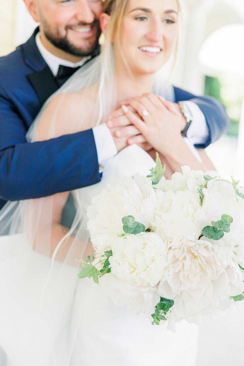 Bride and groom hugging with bridal bouquet