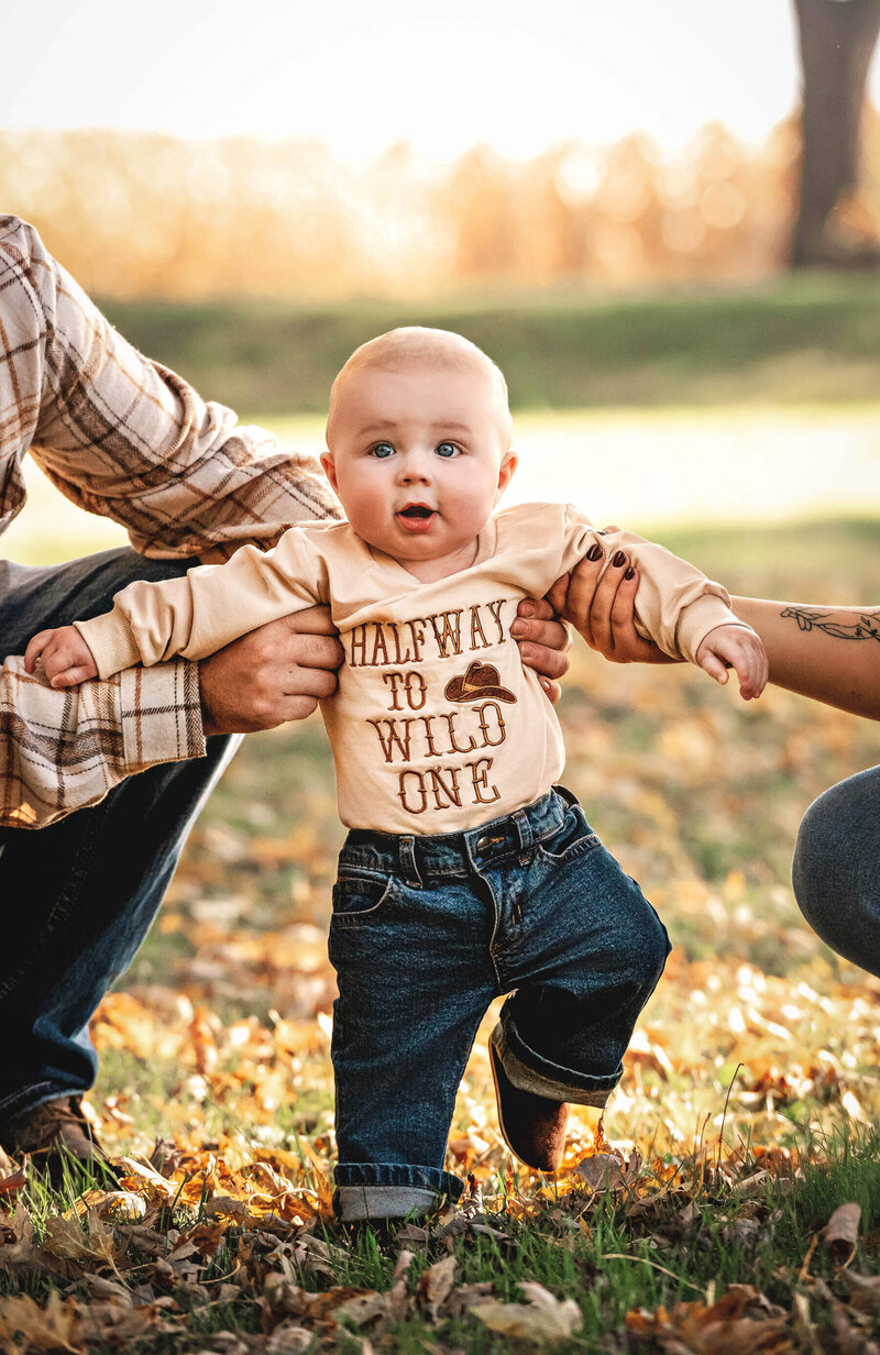 6 month photo of a baby boy outside in a shirt that says halfway to wild one