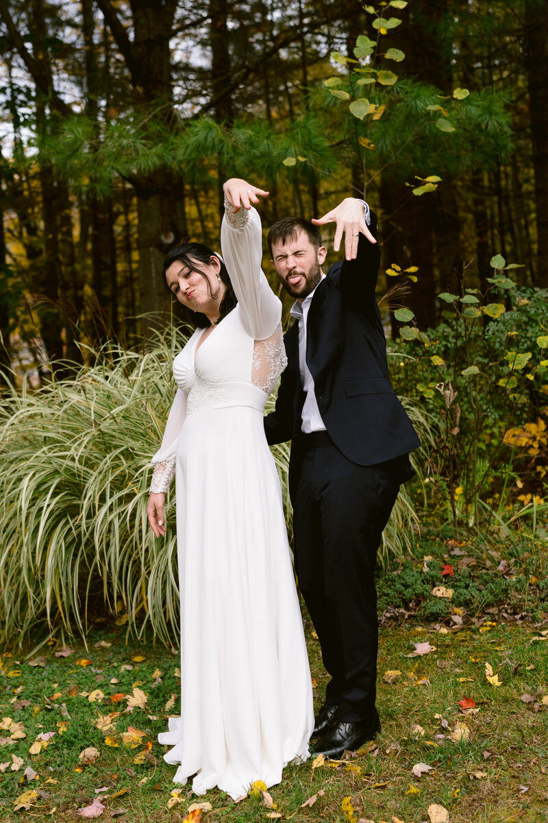 married couple standing together in trees while holding out their hands with rings on it