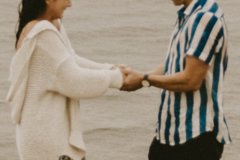 Close-up image of a couple holding hands in front of Lake Michigan