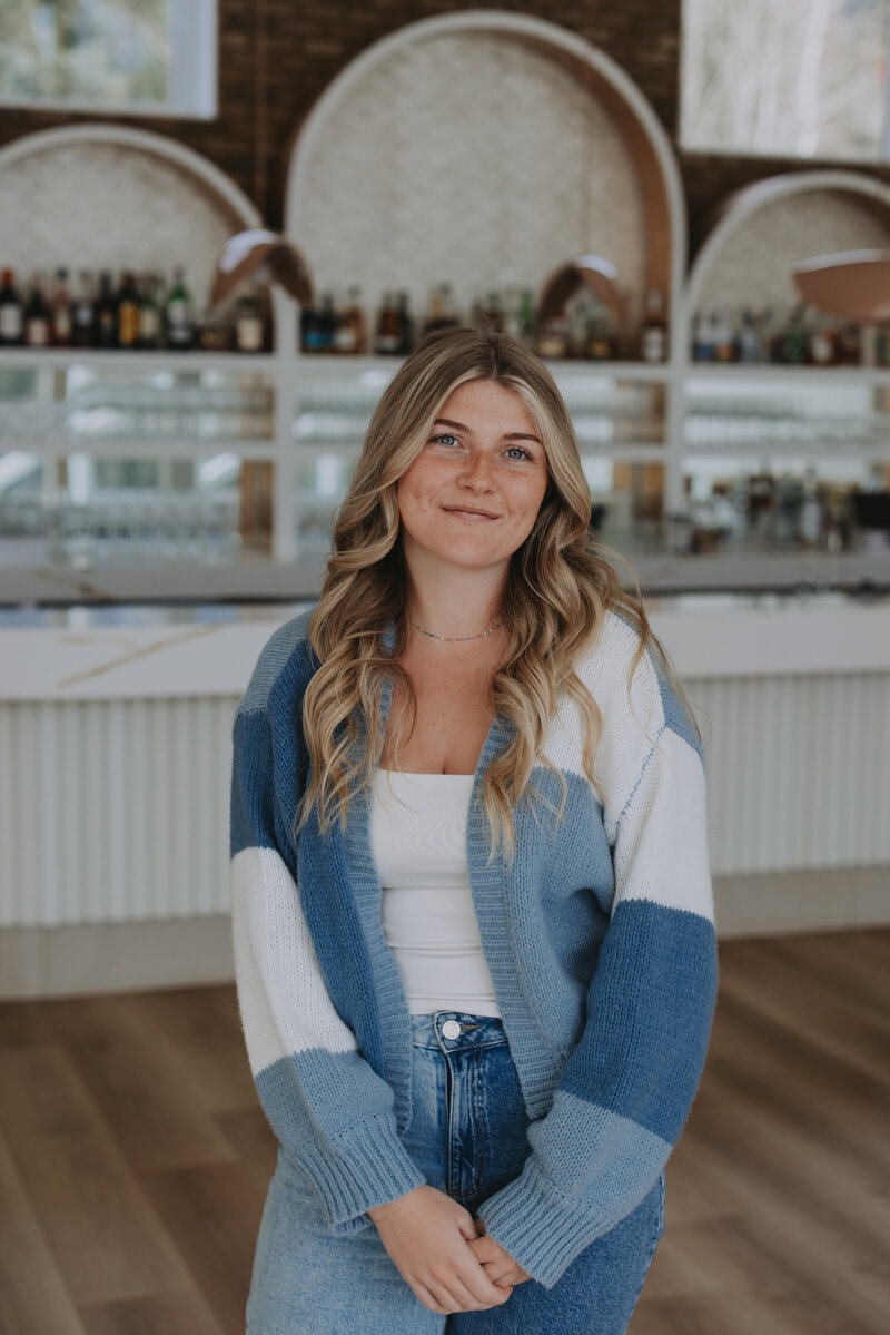 Event planner in cozy winter outfit and grey beanie smiling in snowy Banff forest – Rocky Mountain Wedding Collective