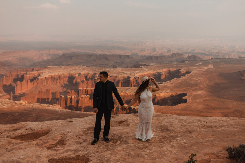 Couple holds hands in front of a canyon during their elopement at Canyonlands National Park