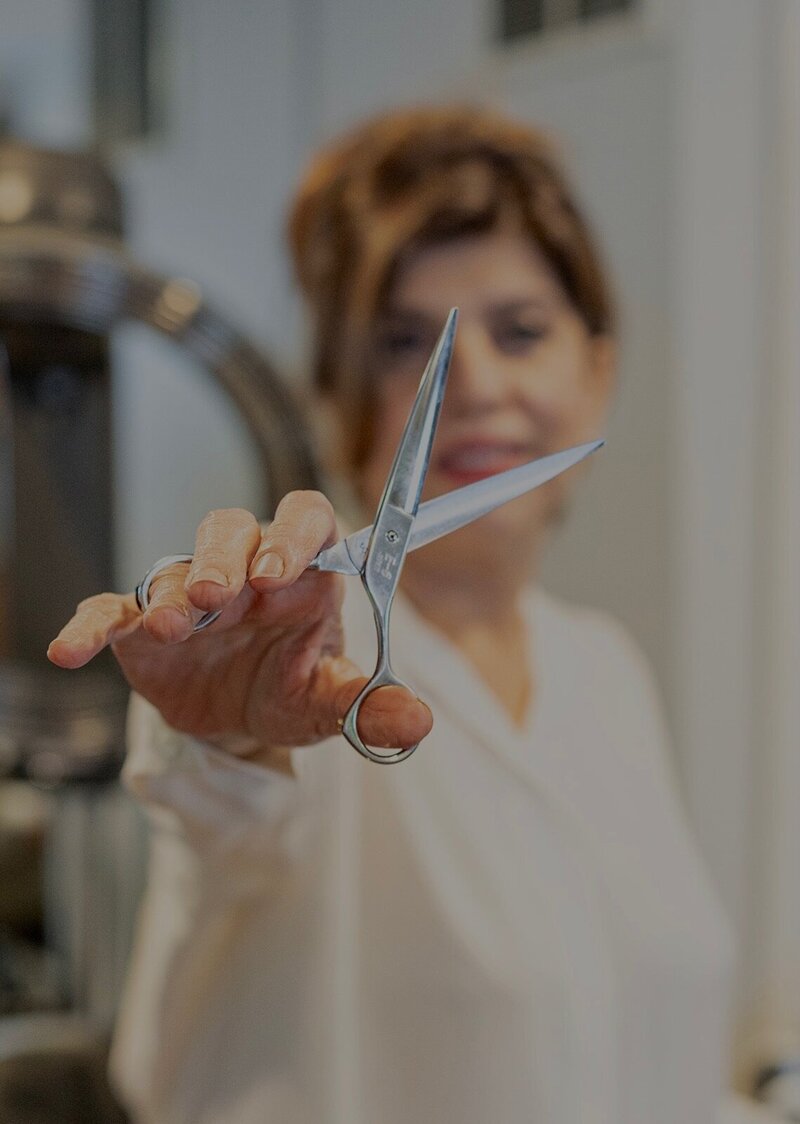 Close-up of Amber, the owner of Laila's Studio, holding professional hairdressing scissors, ready to create a new style.
