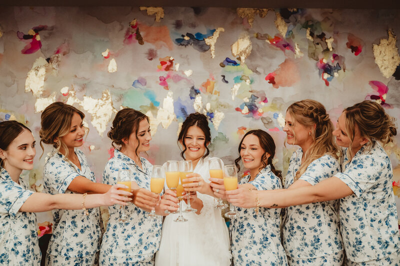 Bride with her bridesmaids cheering's with a glass of champagne