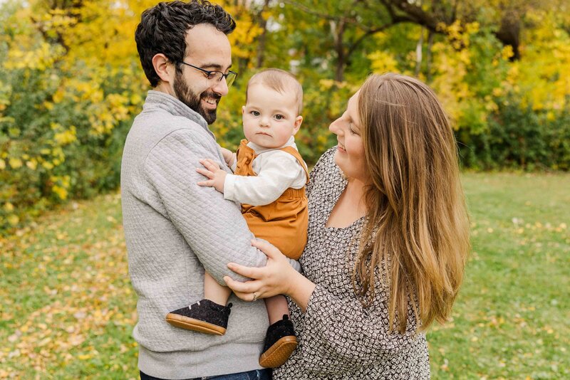 Fall Family Portraits, Mom and Dad holding son in Fall.