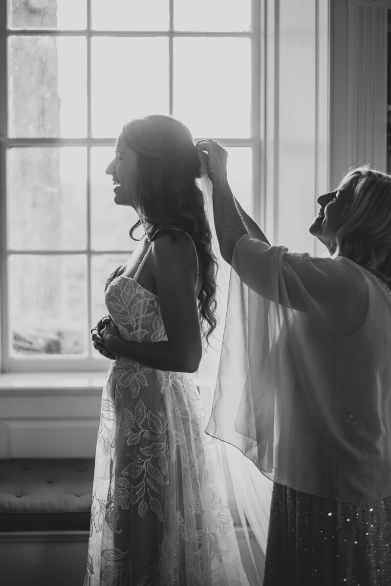 mother of bride helps pin the veil into bride's hair