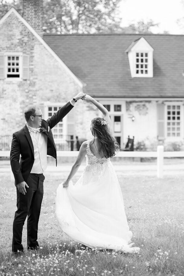 Black and white photo of bride and groom dancing in a field during their Williamsburg wedding, coordinated by Sweet Caroline Events