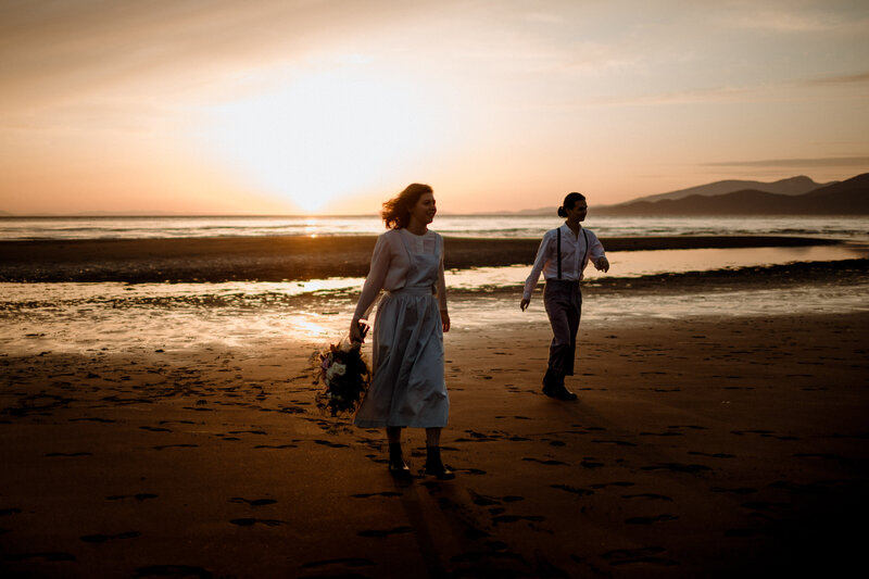 Couple walking on a beach during sunset at their engagement session
