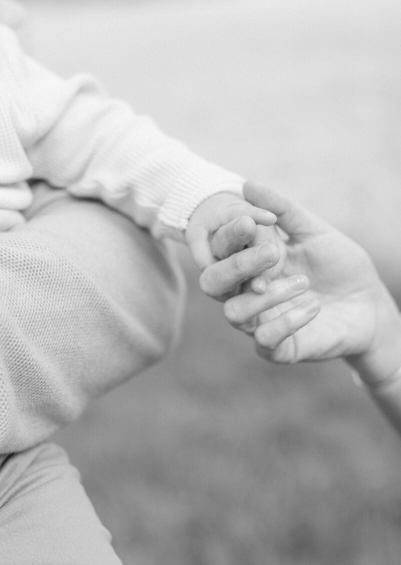 close up image of baby fingers wrapped around moms